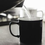 Donna che beve acqua calda al mattino, migliorando colesterolo e glicemia.