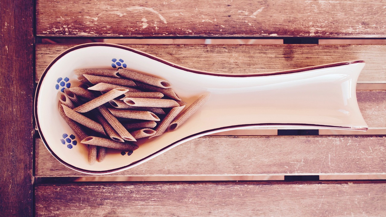 Pasta integrale in un piatto, con ingredienti freschi e salutari attorno, evidenziando i benefici nutrizionali.