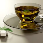 Tazza di tè verde fumante su un tavolo, con un libro aperto accanto.